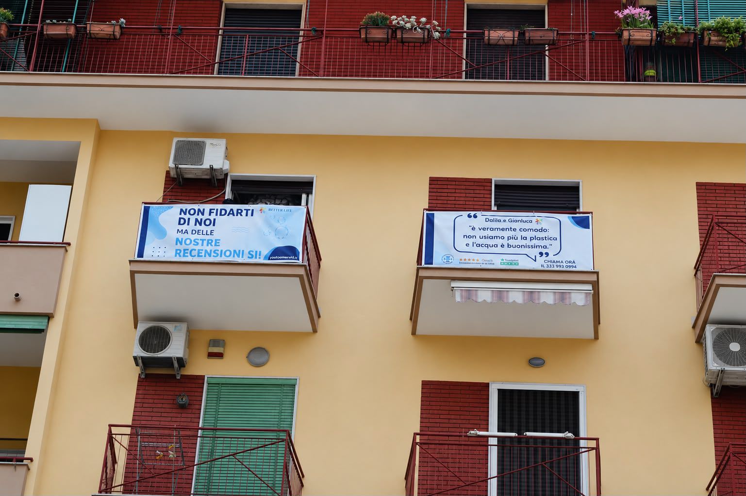 Facciata residenziale con due banner BetterLife montati sui balconi