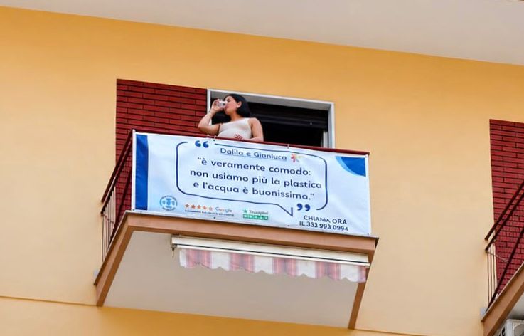 Banner pubblicitario fissato a un balcone su una facciata color ocra